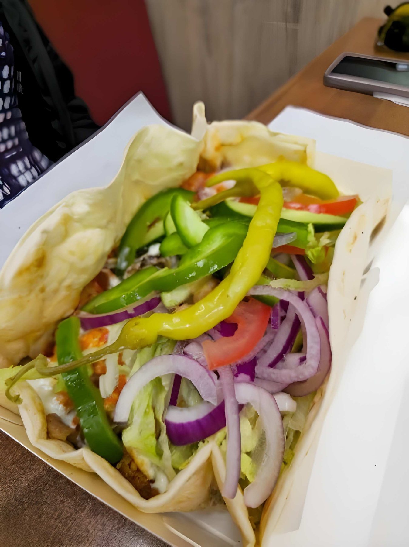 Open kebab box with peppers, red onion and fresh salad