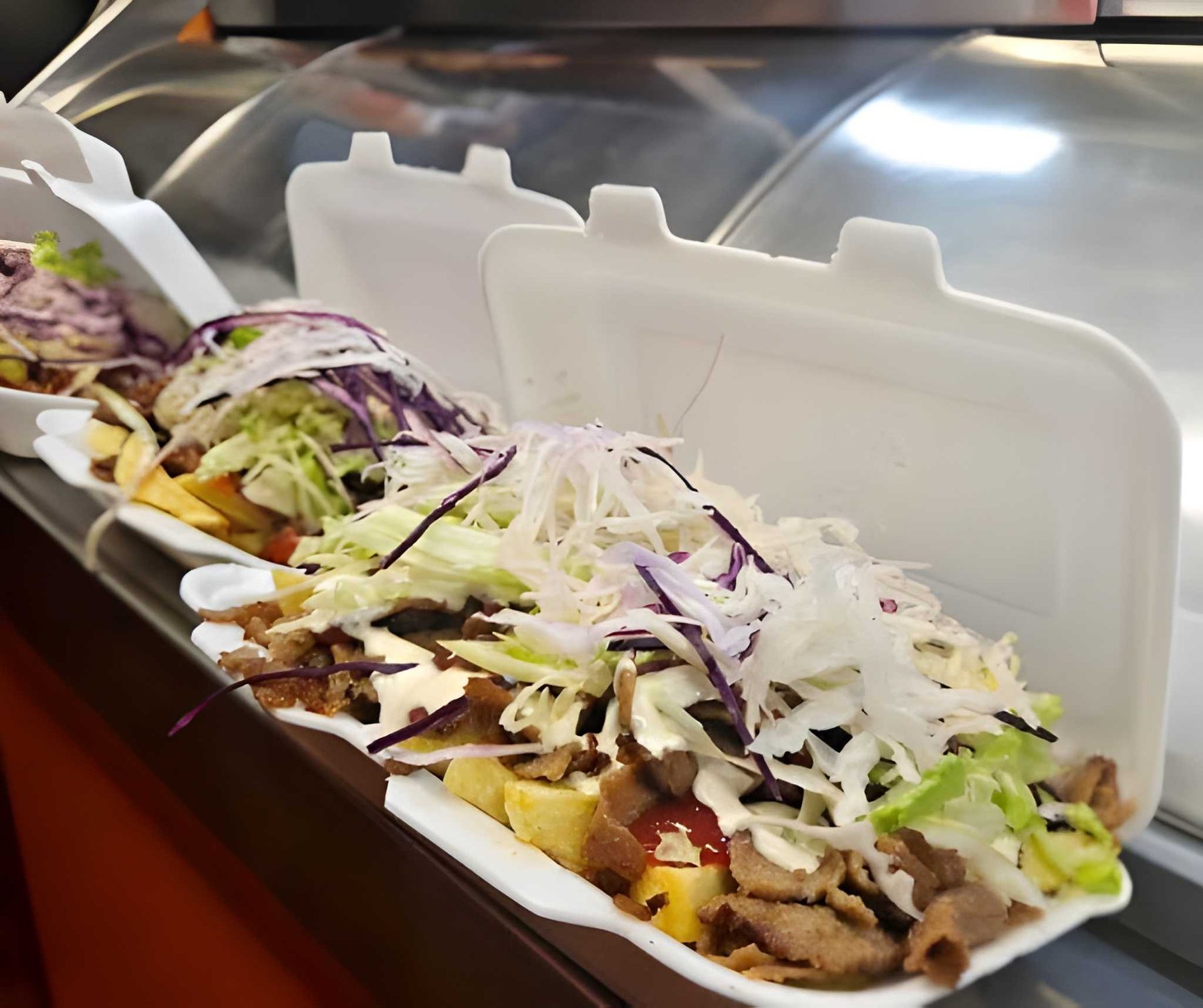 Kebab boxes filled with meat and fresh salad on the counter
