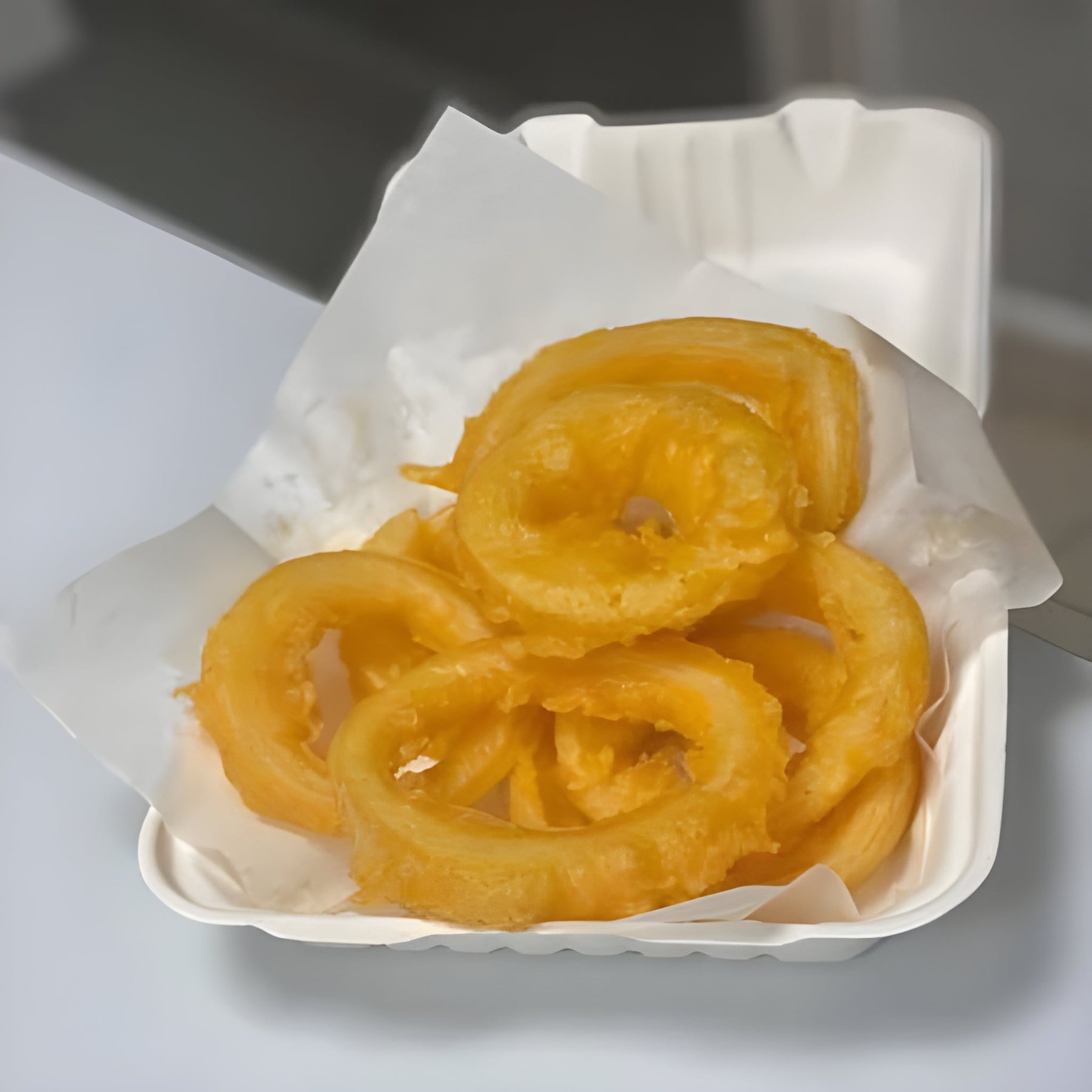 Golden onion rings in a takeaway box